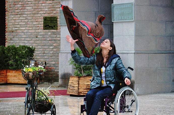 Image of girl in wheelchair throwing shawl in the air 