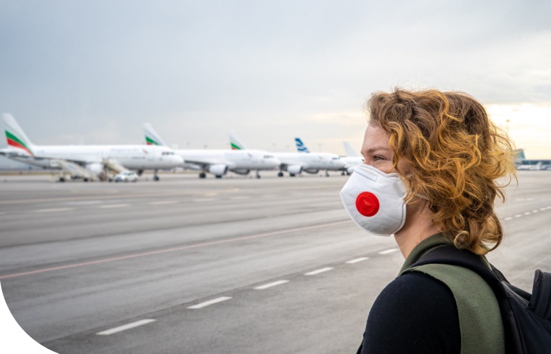 image of woman wearing facemask looking at line of aeroplanes