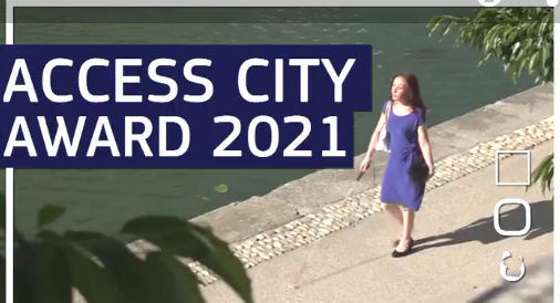 Image of blind female with white stick walking along waterfront. Text Access City Award 2021 