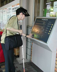 Photo of person with white stick using ticket machine