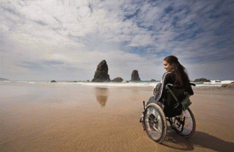 Photo of woman in wheelchair on sandy beach 