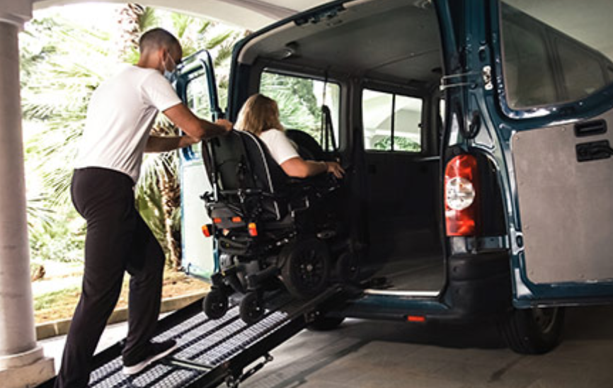 image of wheelchair user entering minivan via ramp with assistance