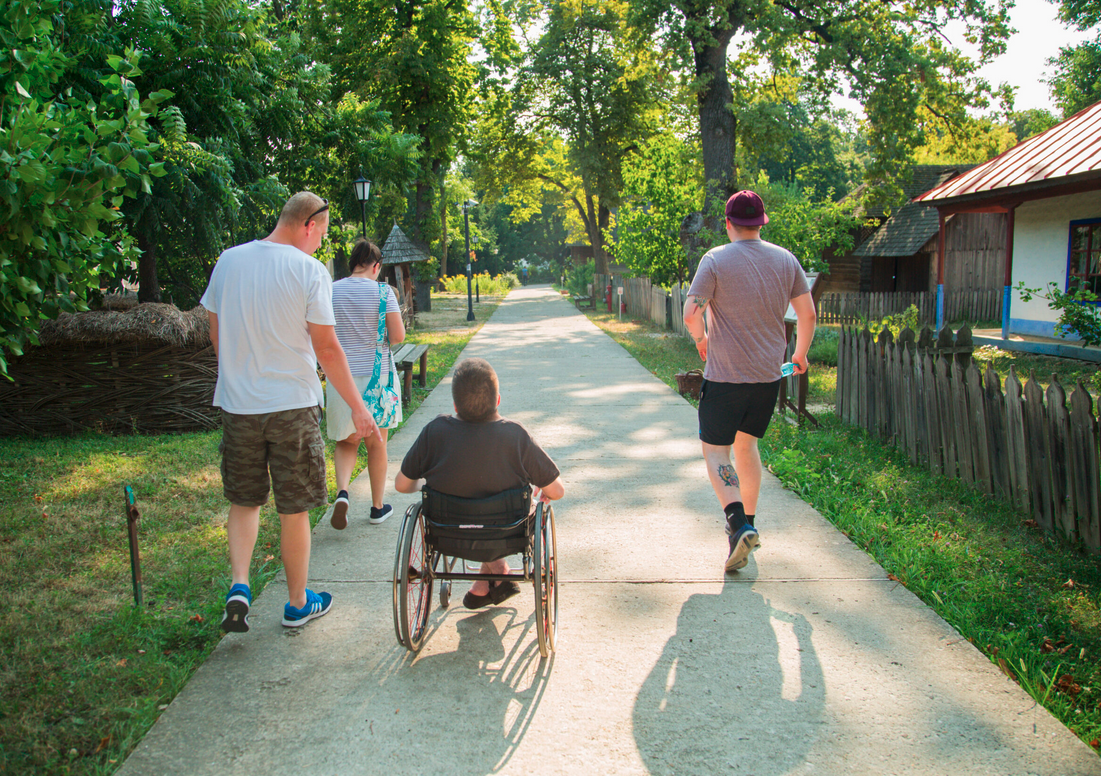 Smooth path in Romania village, with a person using a wheelchair user and 3 persons walking 