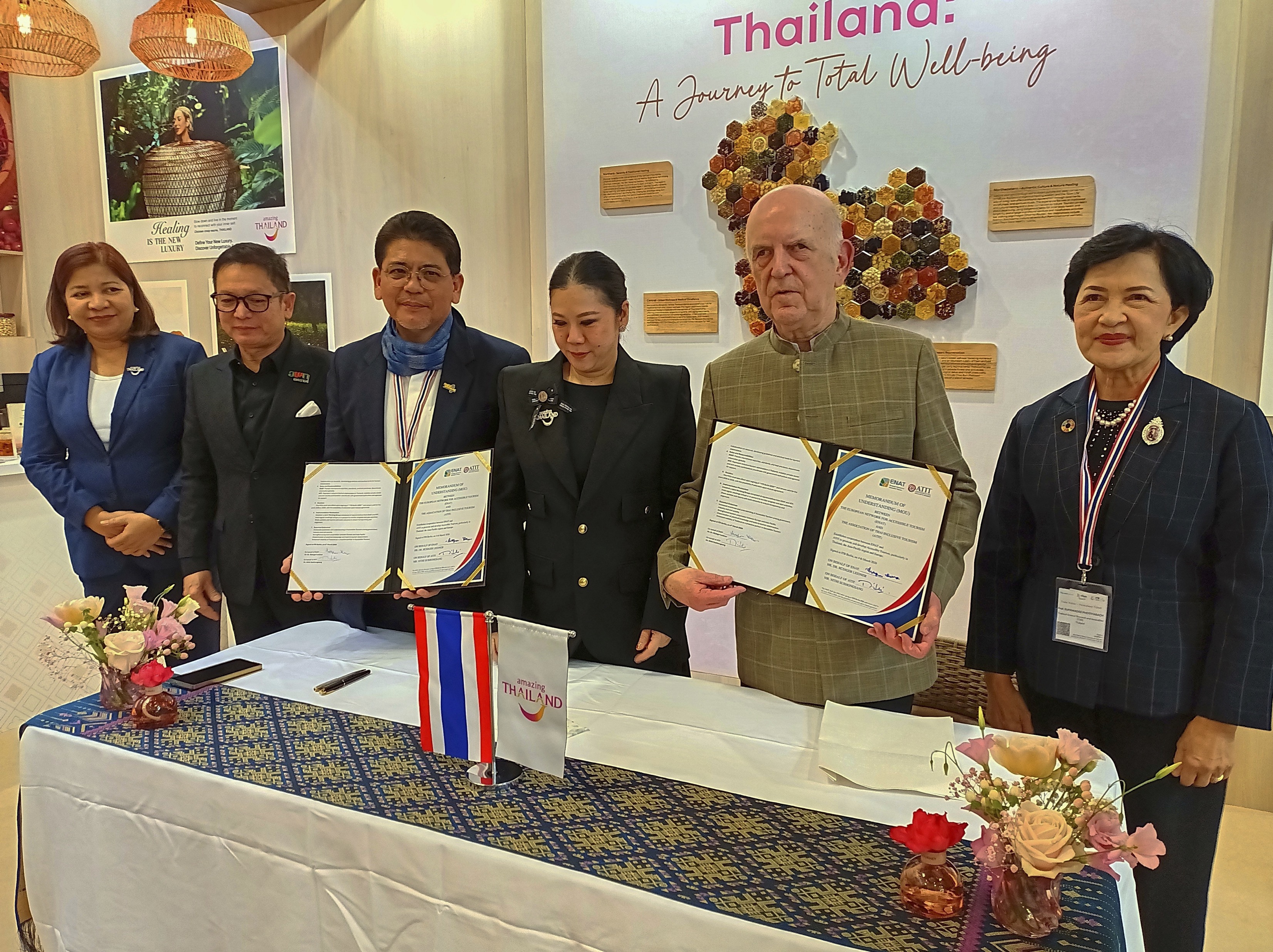 6 male and female dignitaries at the ENAT - ATIT MoU signing ceremony stading behind a table with flowers and flag of Thailand Tahiland    