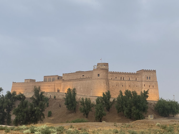 image of the imposing Shush castle with towere and battlements, on a hillside with tall green trees