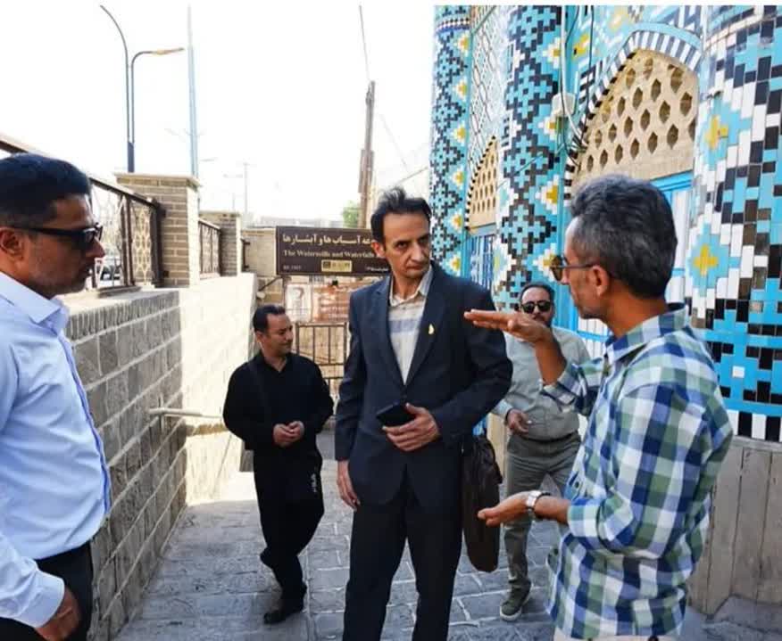 4 men standing by a colourful wall, talkng, at the Shushtar Watermills  