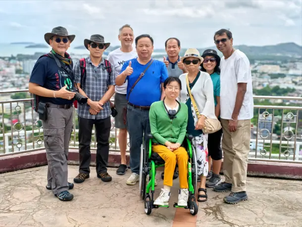A group of 9 friends on a tour at a city viewpoint with one lady in a wheelchair   