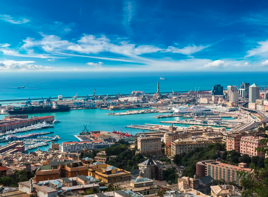 View of Port of Genoa with surrounding buildings, jetties and boats. 